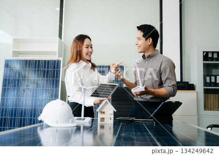 Engineers discuss solar panels and turbines in office, working on clean energy design, sustainable power 134249642