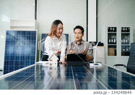 Engineers discuss solar panels and turbines in office, working on clean energy design, sustainable power Engineers discuss solar panels and turbines in office, working on clean energy design, sustainable power 134249644