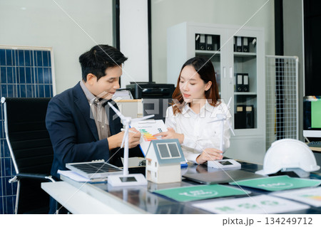Engineers discuss solar panels and turbines in office, working on clean energy design, sustainable power 134249712