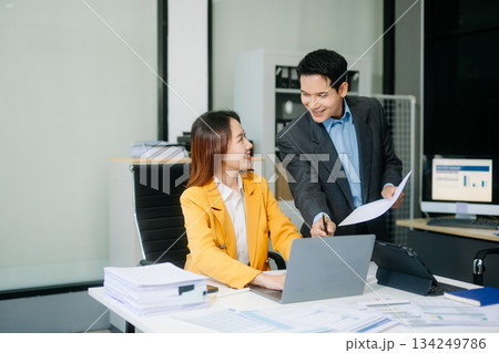 Two asian business workers talking on the smartphone and using laptop at office. 134249786