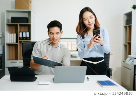 Two business workers talking on the smartphone and using laptop 134249810
