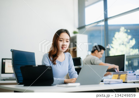 Asian business woman typing laptop and tablet Placed at the table at the office Asian business woman typing laptop and tablet Placed at the table at the office 134249859