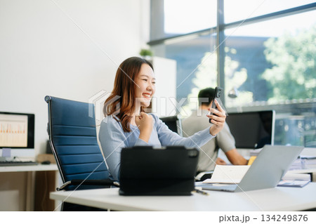 Asian business woman are delighted and happy with the work they do on their tablet, laptop and taking notes 134249876