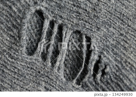 A close view of a gray sweater showing a rip and texture. 134249930