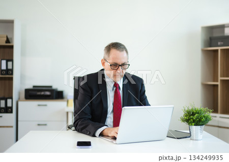 Mature businessman working in office with laptop, tablet, and notes. Perfect for business, finance, accounting Mature businessman working in office with laptop, tablet, and notes. Perfect for business, finance, accounting 134249935