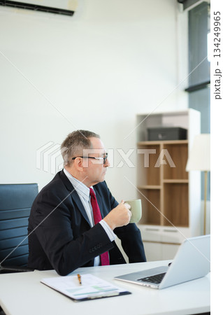 Mature business man executive manager looking at laptop watching online webinar training or having virtual working in office. 134249965