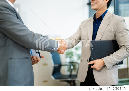 Professional handshake between two businessmen sealing a successful agreement in a modern office Professional handshake between two businessmen sealing a successful agreement in a modern office 134250543