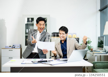 Two excited businessmen cheering with joy in office after success. Concept of teamwork, business win Two excited businessmen cheering with joy in office after success. Concept of teamwork, business win 134250551