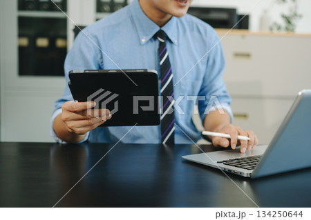 Confident businessman working on laptop, tablet and smartphone at her workplace Confident businessman working on laptop, tablet and smartphone at her workplace 134250644