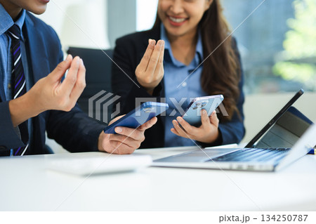Business documents on office table with smart phone and laptop and two colleagues discussing data in the background Business documents on office table with smart phone and laptop and two colleagues discussing data in the background 134250787