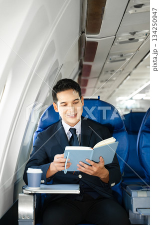 Young Asian executive excels in first class, multitasking with digital tablet, laptop and smartphone. Travel in style, work with grace. 134250947