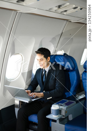 Confident businessman enjoying luxury air travel in first class, working on a tablet with a coffee, blending business, technology, and global connectivity. Confident businessman enjoying luxury air travel in first class, working on a tablet with a coffee, blending business, technology, and global connectivity. 134250964