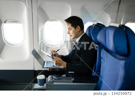 Confident businessman making a phone call in first class, blending luxury air travel with business, technology, and global networking opportunities. 134250972
