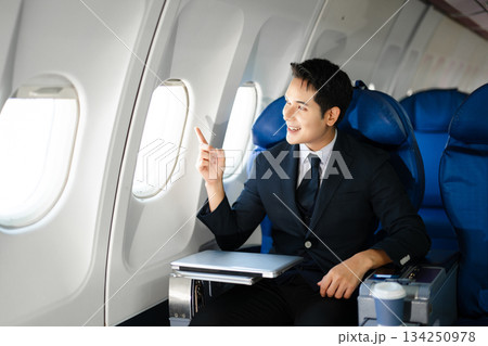 Smiling businessman in a suit giving a thumbs up while seated in first class, symbolizing success, confidence, and luxury air travel for business professionals. Smiling businessman in a suit giving a thumbs up while seated in first class, symbolizing success, confidence, and luxury air travel for business professionals. 134250978