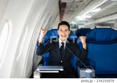 Smiling businessman in a suit giving a thumbs up while seated in first class, symbolizing success, confidence, and luxury air travel for business professionals. Smiling businessman in a suit giving a thumbs up while seated in first class, symbolizing success, confidence, and luxury air travel for business professionals. 134250979