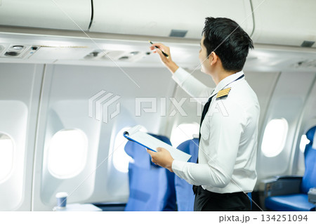 Professional airline pilot inspecting airplane cabin during safety check, perfect for aviation, travel, and airline safety concept stock photography Professional airline pilot inspecting airplane cabin during safety check, perfect for aviation, travel, and airline safety concept stock photography 134251094
