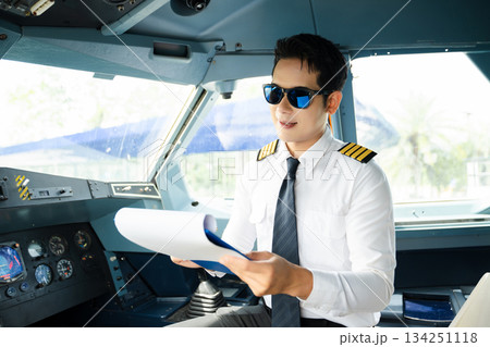 Professional airline pilot in uniform inspecting cockpit control panels during safety checks, ideal for aviation, travel, and airline safety themes. Professional airline pilot in uniform inspecting cockpit control panels during safety checks, ideal for aviation, travel, and airline safety themes. 134251118