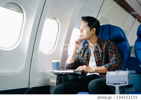 Travel stress, jet lag, or motion sickness. Young man with a headache or fatigue during a long flight. Tired passenger on a business trip. Pain, sit, air, mobile. 134251155