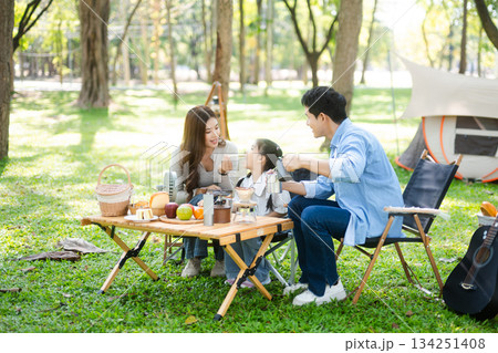 Happy parents and daughter Bakery and Bread Fruit enjoy  in a sunny garden. A joyful summer picnic full of love, food for family, outdoor 134251408