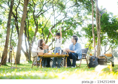 Happy parents and daughter Bakery and Bread Fruit enjoy  in a sunny garden. A joyful summer picnic full of love, food for family, outdoor 134251409