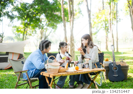 Joyful Asian family camping in a sunny garden, bonding over BBQ, tech, and laughter. Parents and daughter enjoy outdoor Joyful Asian family camping in a sunny garden, bonding over BBQ, tech, and laughter. Parents and daughter enjoy outdoor 134251447