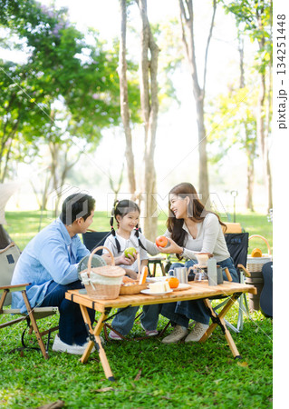Joyful Asian family camping in a sunny garden, bonding over BBQ, tech, and laughter. Parents and daughter enjoy outdoor Joyful Asian family camping in a sunny garden, bonding over BBQ, tech, and laughter. Parents and daughter enjoy outdoor 134251448
