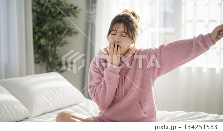 白いベッドの上で伸びをする若い日本人女性 134251583