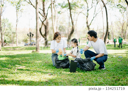 Asian parents and child collect bottles at the park, sharing love, teamwork, and care. A green lifestyle moment promoting recycling, unity 134251719