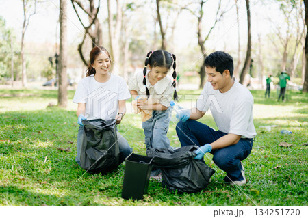 Asian parents and child collect trash in the forest, promoting recycling, unity, and ecology. A heartwarming scene of love, care, teamwork 134251720