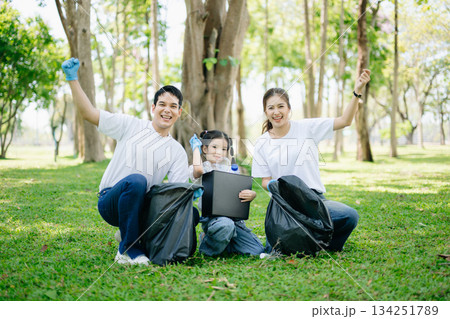 Asian parents and child collect trash in the forest, promoting recycling, unity, and ecology. A heartwarming scene of love, care, teamwork 134251789
