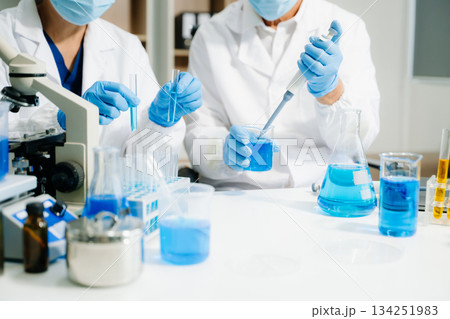 Two scientists in a high-tech lab analyzing biochemical samples, using micro pipettes Two scientists in a high-tech lab analyzing biochemical samples, using micro pipettes 134251983