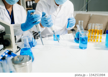 Two scientists in a high-tech lab analyzing biochemical samples, using micro pipettes Two scientists in a high-tech lab analyzing biochemical samples, using micro pipettes 134251994
