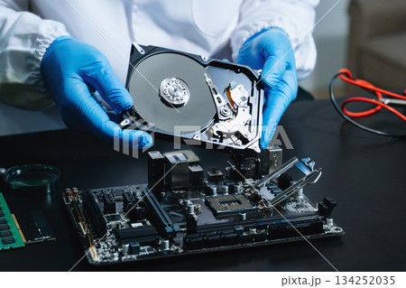 Hard disk drive on the technician's desk and a computer motherboard as a component. the concept of data, hardware 134252035