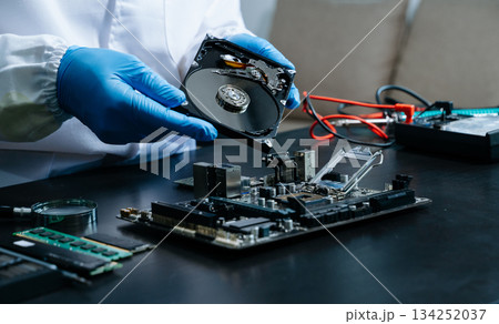 Hard disk drive on the technician's desk and a computer motherboard as a component. the concept of data, hardware 134252037