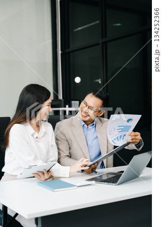 Two business workers talking on the smartphone and using laptop at the office. 134252366