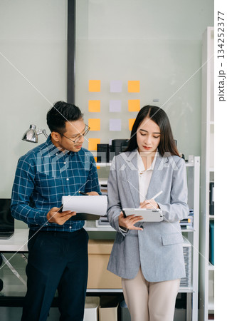 Asian business colleague business presents and explains and using laptop and tablet. Teamwork, financial marketing team Asian business colleague business presents and explains and using laptop and tablet. Teamwork, financial marketing team 134252377