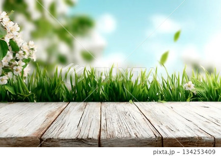 Spring background with fresh grass and white wooden table. Spring apple garden on the background Spring background with fresh grass and white wooden table. Spring apple garden on the background 134253409