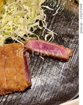 Crispy tonkatsu, a Japanese-style breaded and deep-fried pork cutlet, served with shredded cabbage and drizzled with savory sauce. A delightful balance of crunchy texture and juicy meat. 134253509