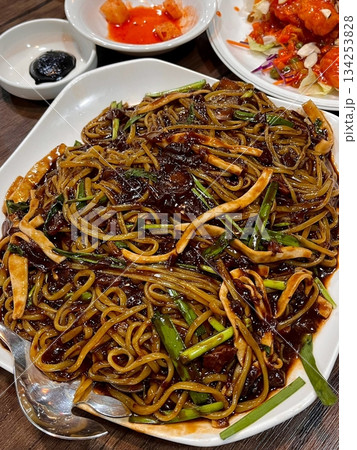 Classic jajangmyeon with thick noodles in a rich black bean sauce, garnished with sliced cucumber and sesame seeds. A beloved Korean-Chinese comfort dish, full of savory depth and flavor. 134253828