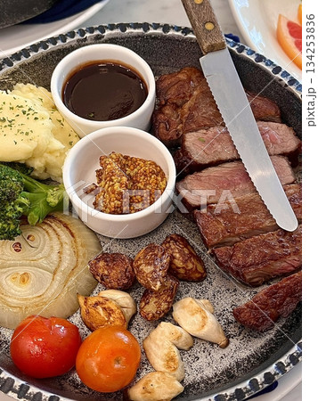Juicy beef steak cooked to perfection with seared golden-brown crust, tender pink interior, and visible grill marks, showcasing its rich texture and mouthwatering detail in close-up view 134253836