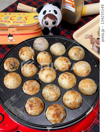 Takoyaki, a popular Japanese street food, are crispy round dough balls filled with octopus, tempura bits, and pickled ginger, topped with takoyaki sauce, bonito flakes, and aonori. Takoyaki, a popular Japanese street food, are crispy round dough balls filled with octopus, tempura bits, and pickled ginger, topped with takoyaki sauce, bonito flakes, and aonori. 134255149