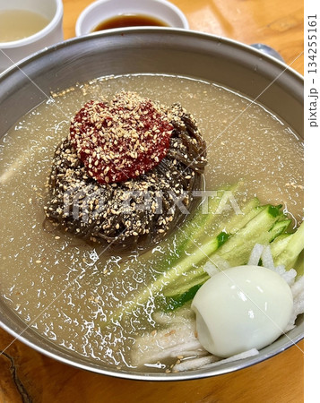 Chilled, chewy naengmyeon noodles in tangy broth paired with juicy, savory mandu dumplings, offering a perfect balance of refreshing coolness and hearty comfort in every delicious Korean bite. Chilled, chewy naengmyeon noodles in tangy broth paired with juicy, savory mandu dumplings, offering a perfect balance of refreshing coolness and hearty comfort in every delicious Korean bite. 134255161