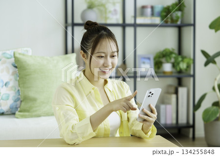 リビングでスマホを手に持って笑う日本人女性のポートレート リビングでスマホを手に持って笑う日本人女性のポートレート 134255848