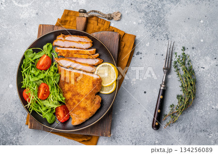 Fried Weiner schnitzel steak, veal breaded meat with salad on a plate. grey background. top view Fried Weiner schnitzel steak, veal breaded meat with salad on a plate. grey background. top view 134256089