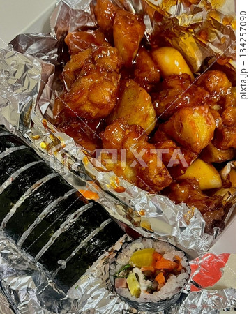 Crispy Korean fried chicken with golden coating served alongside neatly sliced kimbap rolls filled with colorful ingredients, creating a delicious and visually appealing combination Crispy Korean fried chicken with golden coating served alongside neatly sliced kimbap rolls filled with colorful ingredients, creating a delicious and visually appealing combination 134257090