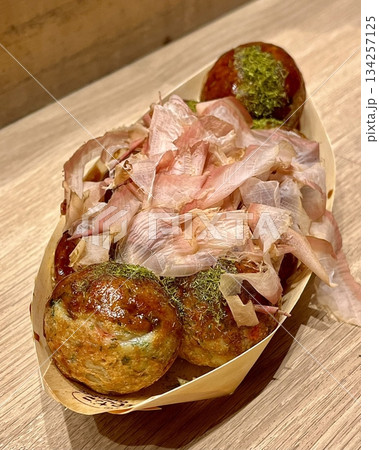 Takoyaki, a popular Japanese street food, are crispy round dough balls filled with octopus, tempura bits, and pickled ginger, topped with takoyaki sauce, bonito flakes, and aonori. Takoyaki, a popular Japanese street food, are crispy round dough balls filled with octopus, tempura bits, and pickled ginger, topped with takoyaki sauce, bonito flakes, and aonori. 134257125