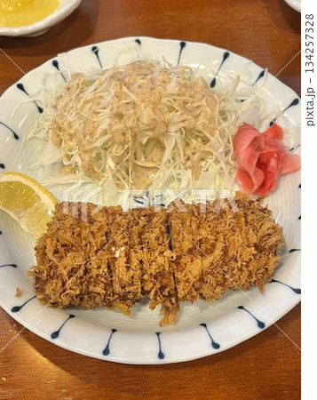 Crispy tonkatsu, a Japanese-style breaded and deep-fried pork cutlet, served with shredded cabbage and drizzled with savory sauce. A delightful balance of crunchy texture and juicy meat. Crispy tonkatsu, a Japanese-style breaded and deep-fried pork cutlet, served with shredded cabbage and drizzled with savory sauce. A delightful balance of crunchy texture and juicy meat. 134257328