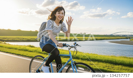 若い女性が川沿いでサイクリング 134257757