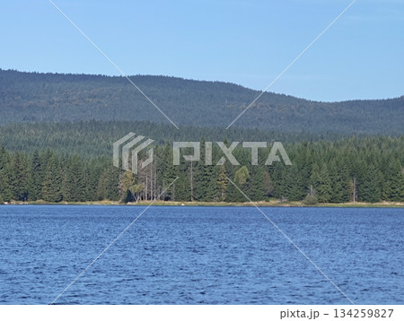 serene body of water encompassed by multitiered forested hills under bright sky perfect 134259827