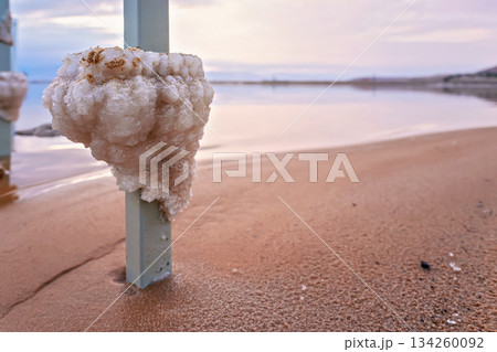Salt crystals formed on steel bar at the Dead Sea shore, closeup detail, blurred beach and water background Salt crystals formed on steel bar at the Dead Sea shore, closeup detail, blurred beach and water background 134260092
